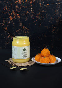 Jar of Ekaris A2 Gir Cow Ghee with motichoor ladoos on a dark background